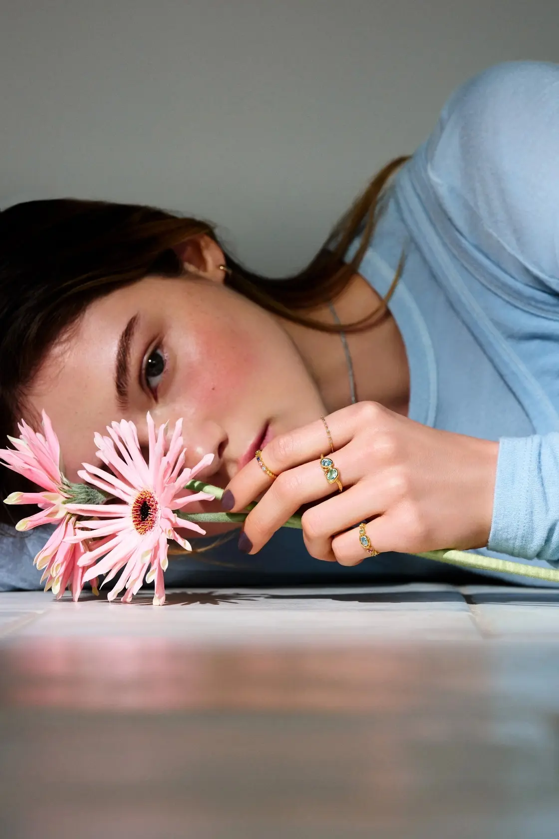 ピンクの花を持ち、リングをつけたモデル